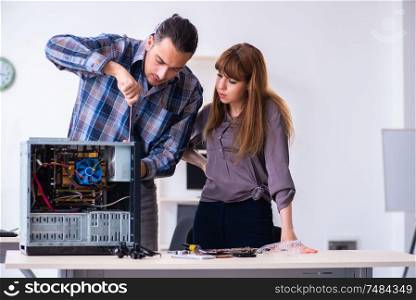 The two repairmen repairing desktop computer . Two repairmen repairing desktop computer