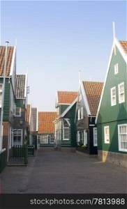 The typical style Dutch fishermans&rsquo; houses on the Peninsula of Marken. The quaint wooden gables, and the archetypal green and white paint in a deserted street during a summer evening.