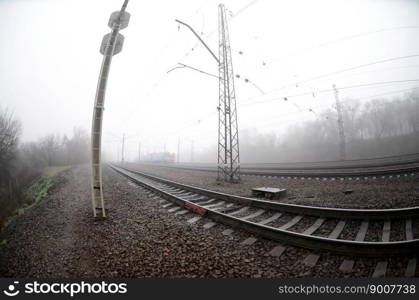 The Ukrainian suburban train rushes along the railway in a misty morning. Fisheye photo with increased distortion