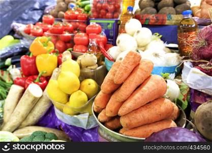 The vegetable market sells many different vegetables, such as carrots, tomatoes, onions, beets, potatoes, parsley roots, parsnips, eggplants, and lemons and sunflower oil.. Carrots, tomatoes, onions, peppers and other vegetables, root vegetables and lemons, sunflower oil are sold on the market shelves.