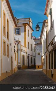 The view of narrow paved street of Evora with the cozy white houses. Evora. Alentejo. Portugal.