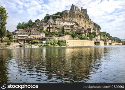 the village of beynac et cazenac with its medieval castle on the cliff reflecting in dordogne river