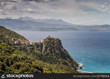 The Village of Nonza on Cap Corse in Corsica with snow capped mountains and the Desert des Agriates in the background