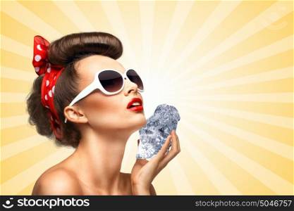 The vintage photo of a glamorous vintage pin-up girl holding a cool ice cube on her skin for rejuvenation on colorful abstract cartoon style background.