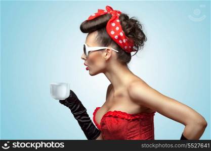 The vintage photo of glamour pin-up girl wearing vintage gloves and cooling a hot cup of coffee.