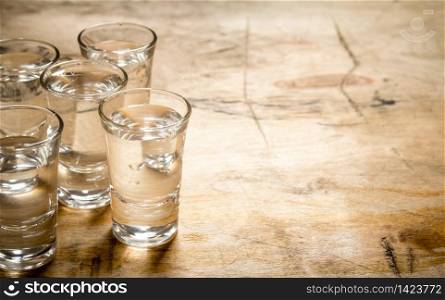 The vodka glass. On a wooden background.. The vodka glass.