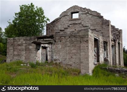 The walls of an abandoned house on a background of green grass.