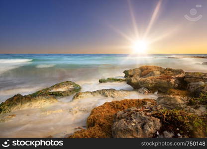 The warm sunset at the beach with some rocks