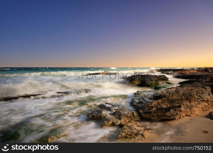 The warm sunset at the beach with some rocks