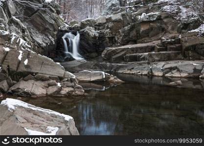 The waterfall at Scott s Run Nature Preserve in Northern Virginia under a cloudy afternoon winter sky with a light dusting of snow on the rocks.