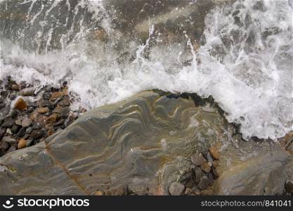 The wave rolls on a rocky shore, aerial view
