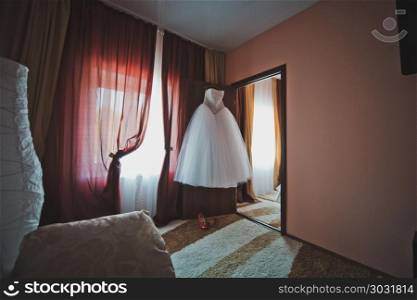 The wedding dress hangs in a room.. Room of the bride before wedding 2229.