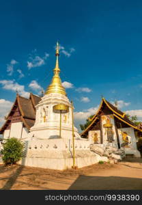 The white and golden pagoda in front of Chapel and ordination hall with blue sky background. The Buddhist temple in Chiang mai, Thailand.