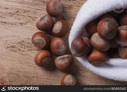 The white bag with the unshelled nuts. The untreated nuts in shell in bag on wooden Board