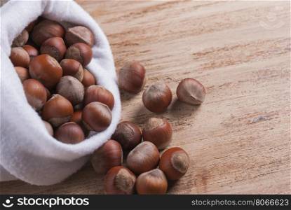 The white bag with the unshelled nuts. The untreated nuts in shell in bag on wooden Board