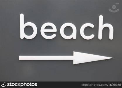 The white word beach of hanging on a gray wall. pointer arrow beach right.. The white word beach of hanging on a gray wall. pointer arrow beach right