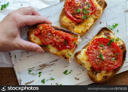 The whole wheat bread is made of grilled with various cheeses on sliced and served with tomato slices and thyme-parsley on top.