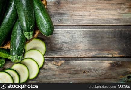 The whole zucchini the basket and slices of zucchini. On wooden background. The whole zucchini the basket and slices of zucchini.