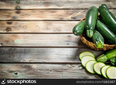 The whole zucchini the basket and slices of zucchini. On wooden background. The whole zucchini the basket and slices of zucchini.