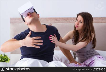 The wife and husband with virtual reality goggles in the bed. Wife and husband with virtual reality goggles in the bed
