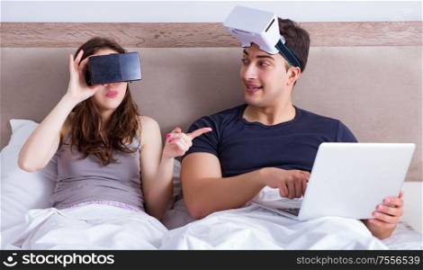 The wife and husband with virtual reality goggles in the bed. Wife and husband with virtual reality goggles in the bed
