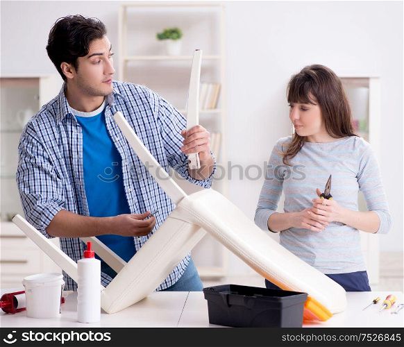 The wife helping husband to repair broken chair at home. Wife helping husband to repair broken chair at home