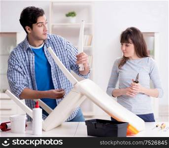 The wife helping husband to repair broken chair at home. Wife helping husband to repair broken chair at home