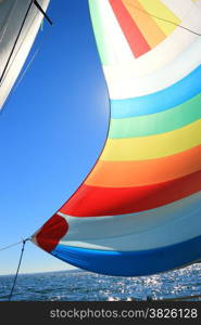 The wind has filled the spinnaker on sailing yacht. Detail of a colorful sail against the deep blue sky.