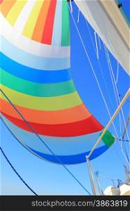 The wind has filled the spinnaker on sailing yacht. Detail of a colorful sail against the deep blue sky.