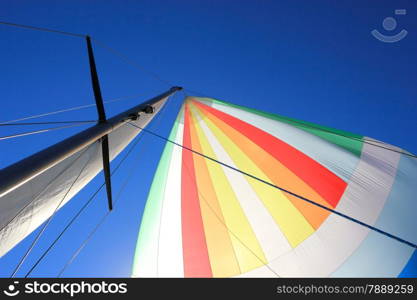 The wind has filled the spinnaker on sailing yacht. Detail of a colorful sail against the deep blue sky.