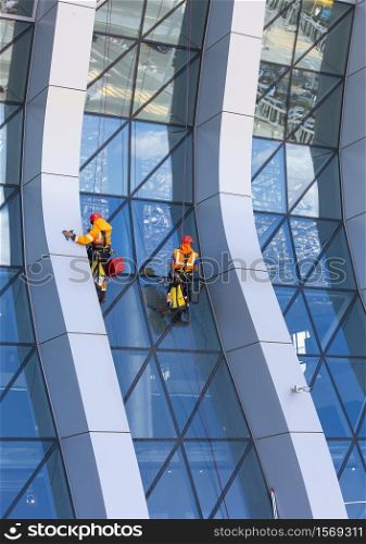 The window cleaner working on a glass facade modern skyscraper