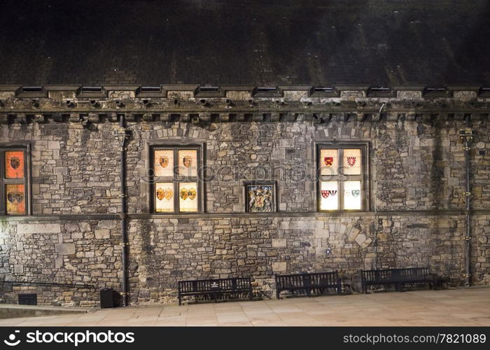 The windows of the Great Hall of Edinburgh Castle glow at night from across the courtyard.