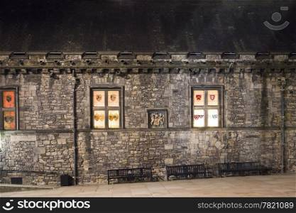 The windows of the Great Hall of Edinburgh Castle glow at night from across the courtyard.