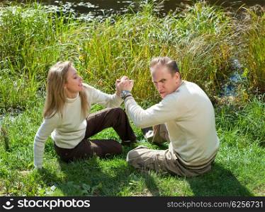 The woman and the man for fun fight on a grass at the lake