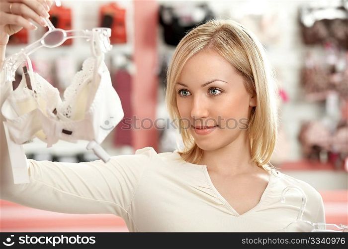 The woman chooses a brassiere among set in a boutique