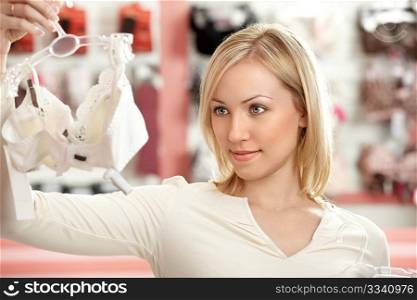 The woman chooses a brassiere among set in a boutique