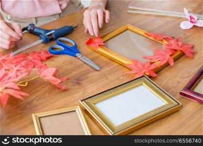 The woman decorating picture frame in scrapbooking concept. Woman decorating picture frame in scrapbooking concept