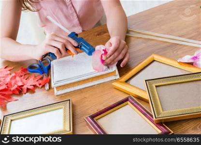 The woman decorating picture frame in scrapbooking concept. Woman decorating picture frame in scrapbooking concept