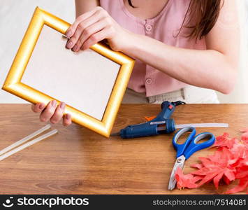 The woman decorating picture frame in scrapbooking concept. Woman decorating picture frame in scrapbooking concept