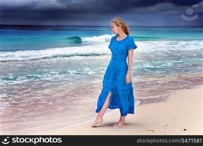 The woman in a long blue dress goes on the stormy sea coast