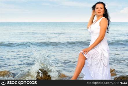The woman in a white sundress on seacoast. A picturesque landscape