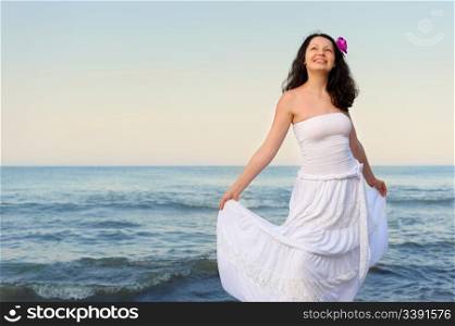 The woman in a white sundress on seacoast. A picturesque landscape