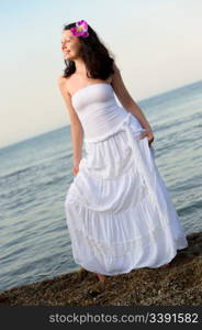 The woman in a white sundress on seacoast. A picturesque landscape