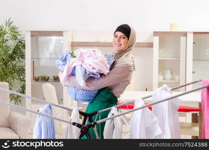The woman in hijab doing clothing ironing at home. Woman in hijab doing clothing ironing at home