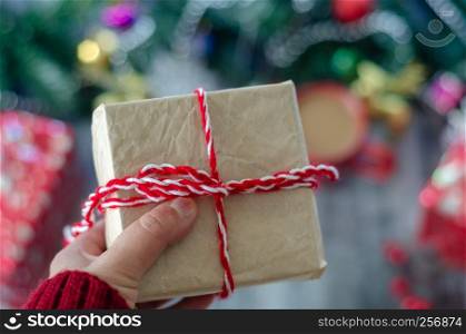 The woman is holding a gift package in hand.Christmas background with decorations and gift boxes.,blurred background.