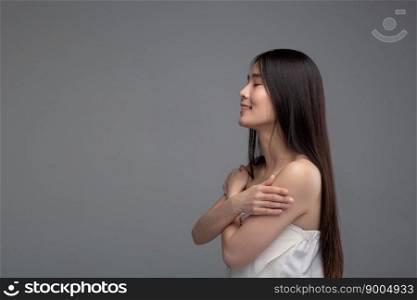 The woman is wearing a strapless shirt that stands with her arms crossed,Taken from the left hand side