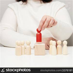 the woman keeps the red wooden figurine separate from the group. Career growth concept, unique person. Finding a talented employee