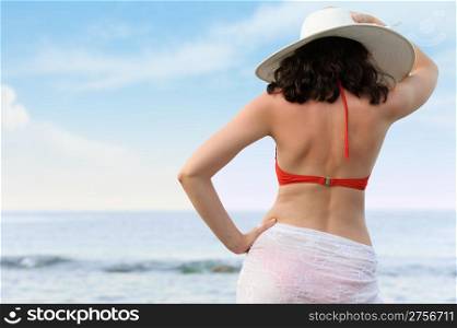 The woman on sea coast in a hat. The rear view