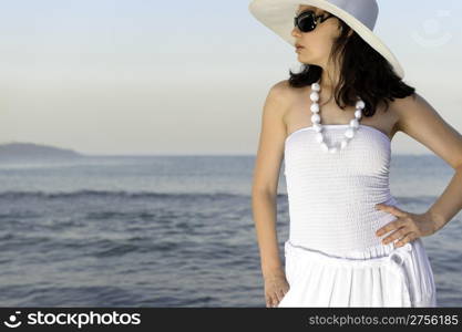 The woman on seacoast. In sun glasses, a sundress, a hat.