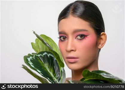 The woman put on pink makeup and decorated with leaves. Isolated on white background